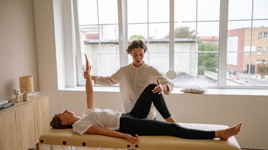 Physical therapist helping client laying down