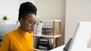 Young professional black woman wearing glasses working on computer