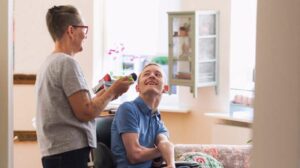 Middle-aged female therapist assisting young man in wheelchair