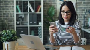 woman at desk entering credit card info into her phone